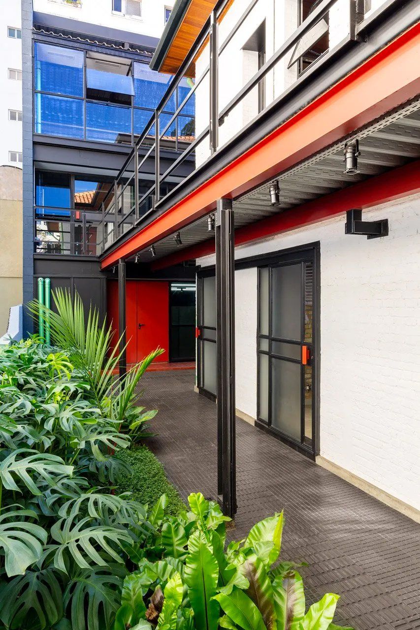 Um prédio com porta vermelha e uma passarela coberta entre dois prédios.