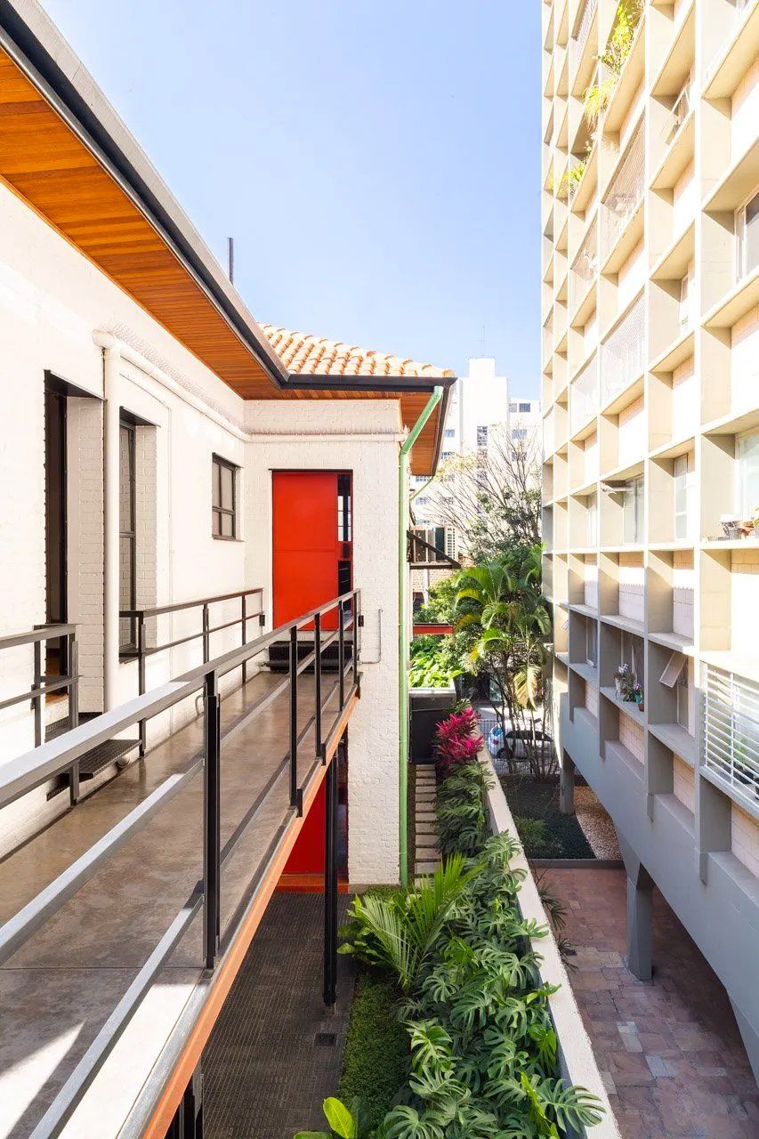 Há uma varanda entre dois edifícios com uma porta vermelha.