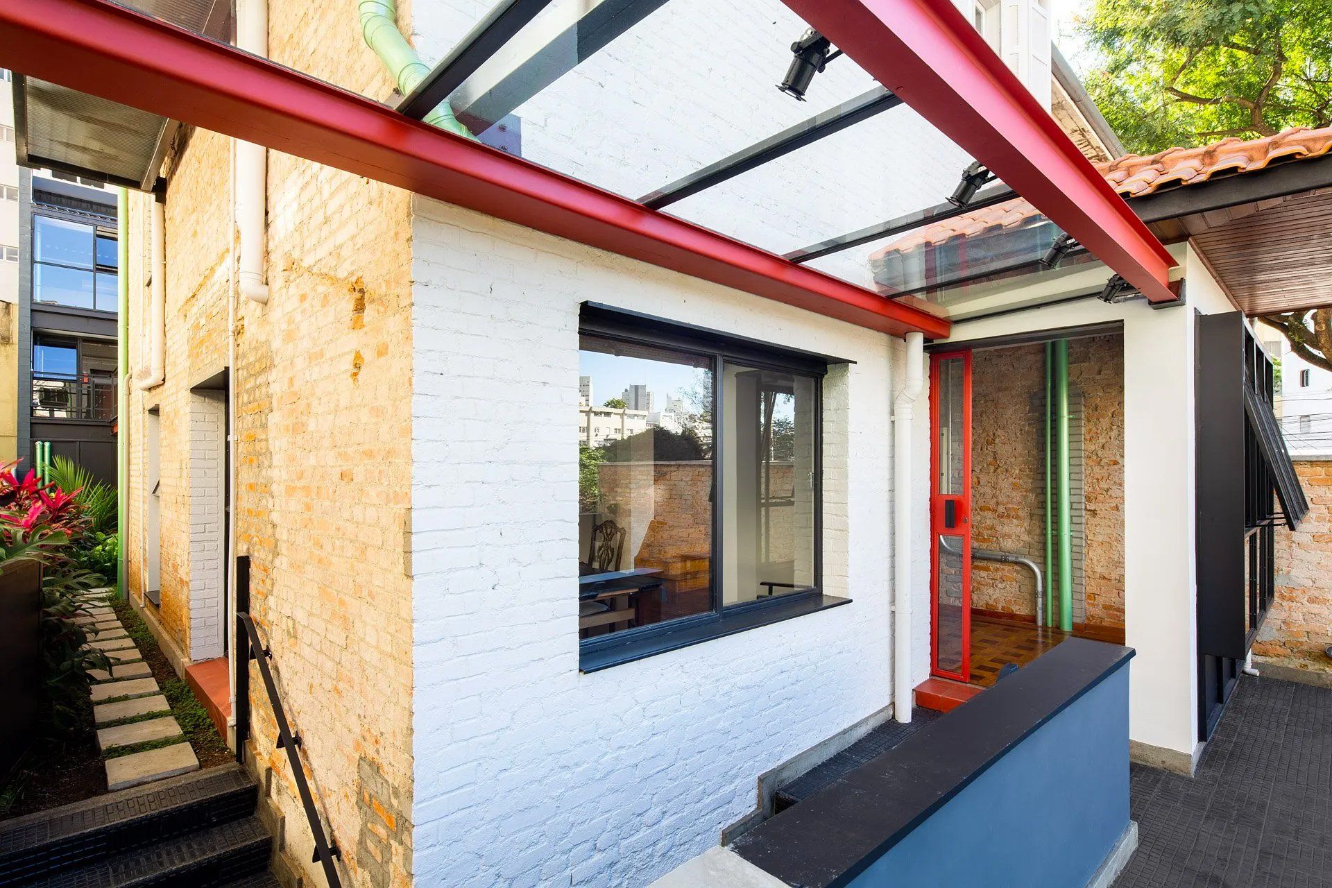 Um prédio de tijolos brancos com telhado vermelho e uma janela