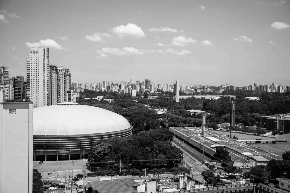 Uma foto em preto e branco de uma cidade com um estádio em primeiro plano.