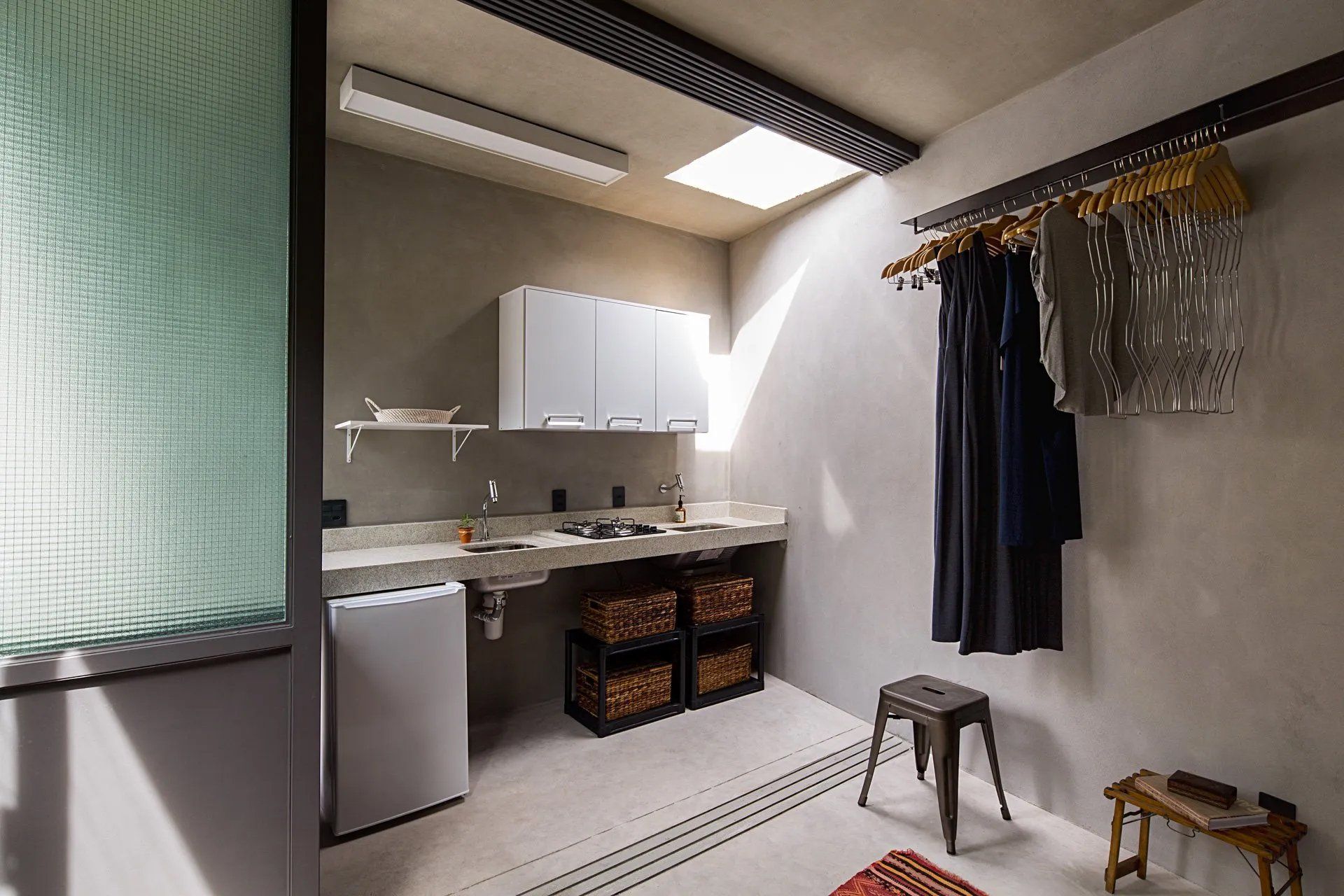 Uma lavanderia com roupas penduradas na parede e uma pia.