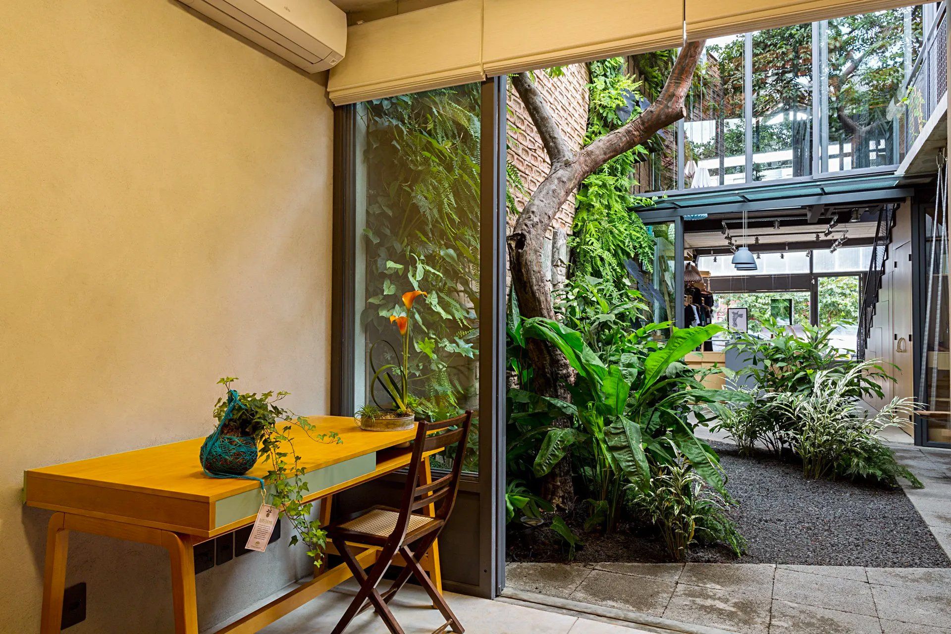 Uma sala com mesa e cadeiras e vista para o jardim através de uma janela.