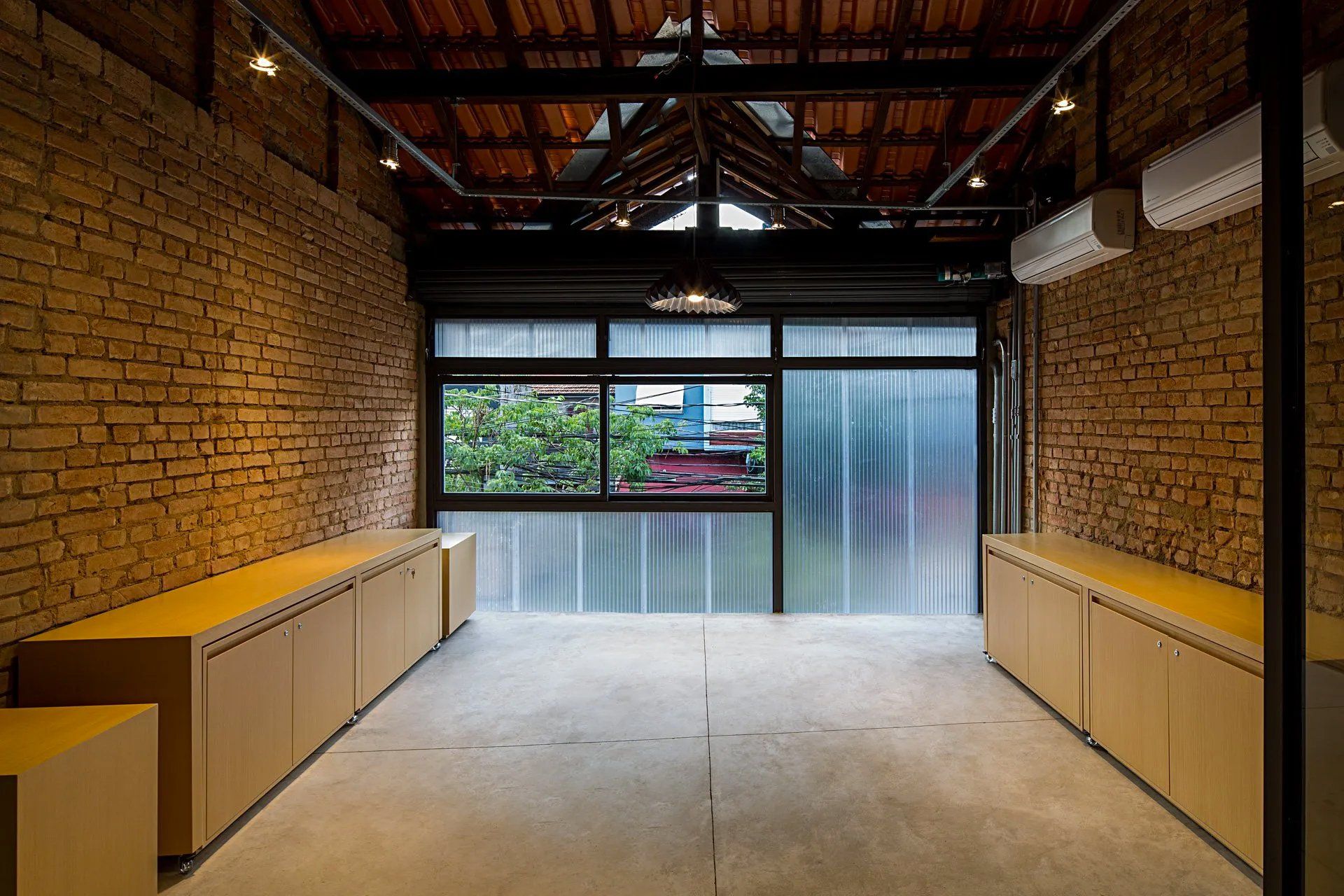 Uma sala vazia com uma parede de tijolos e uma grande janela.