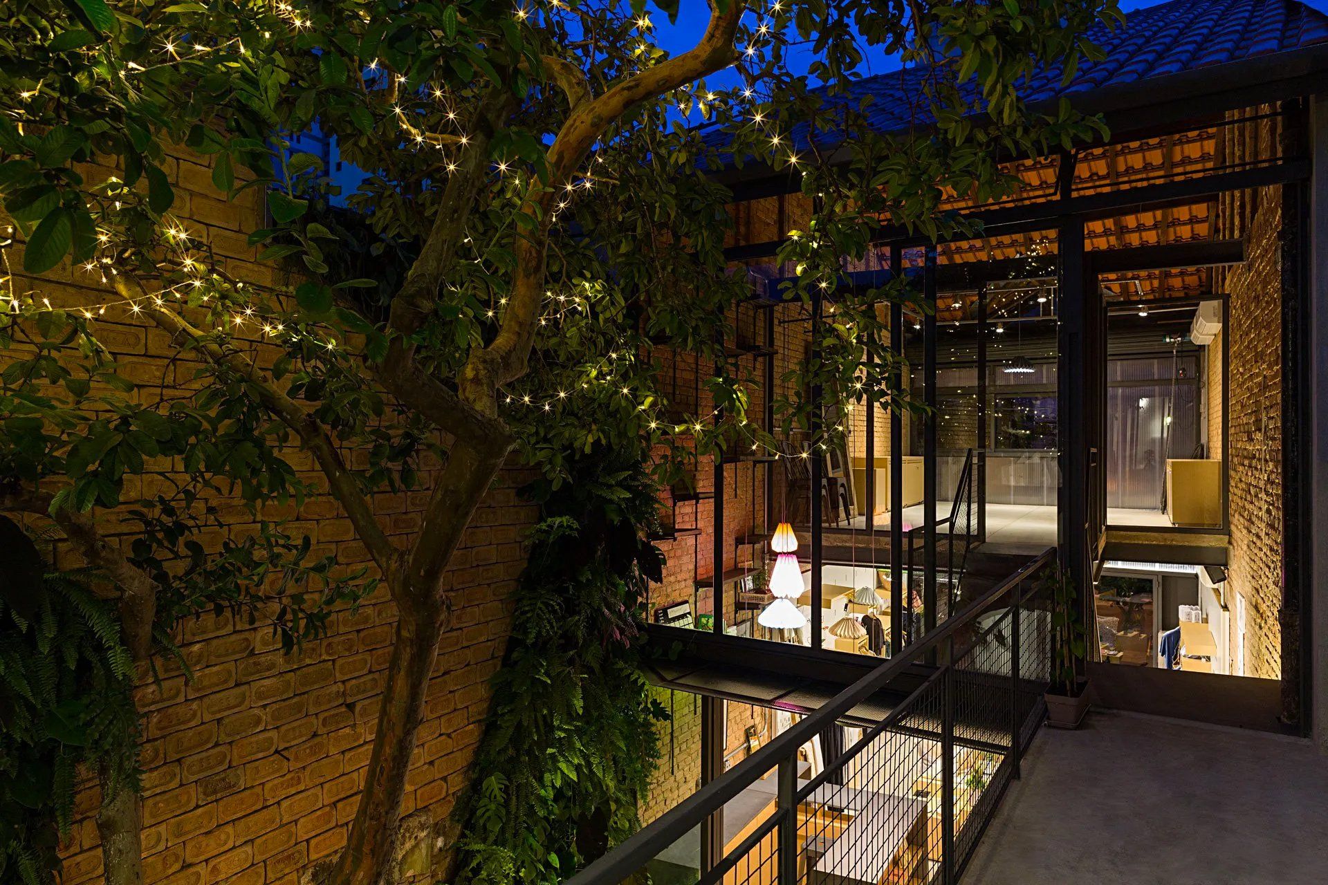 Uma varanda com luzes de natal penduradas nas árvores em frente a um prédio.