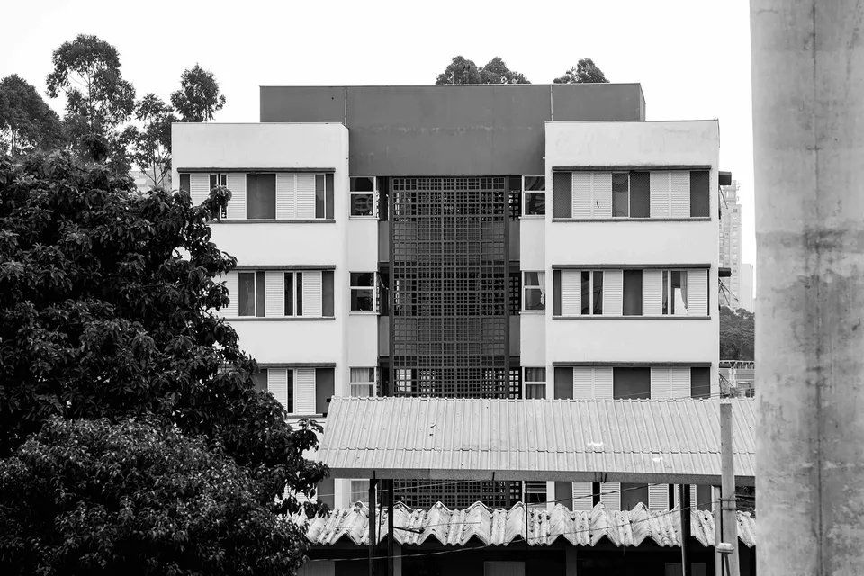 Uma foto em preto e branco de um prédio com árvores ao fundo