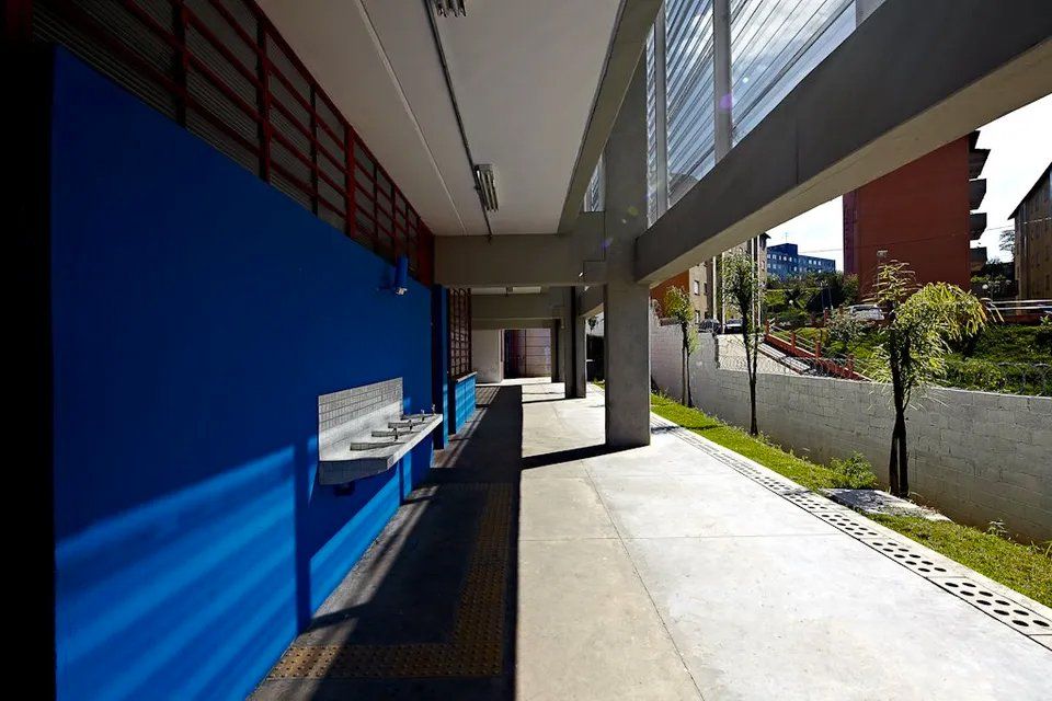 Um longo corredor com paredes azuis e algumas pias