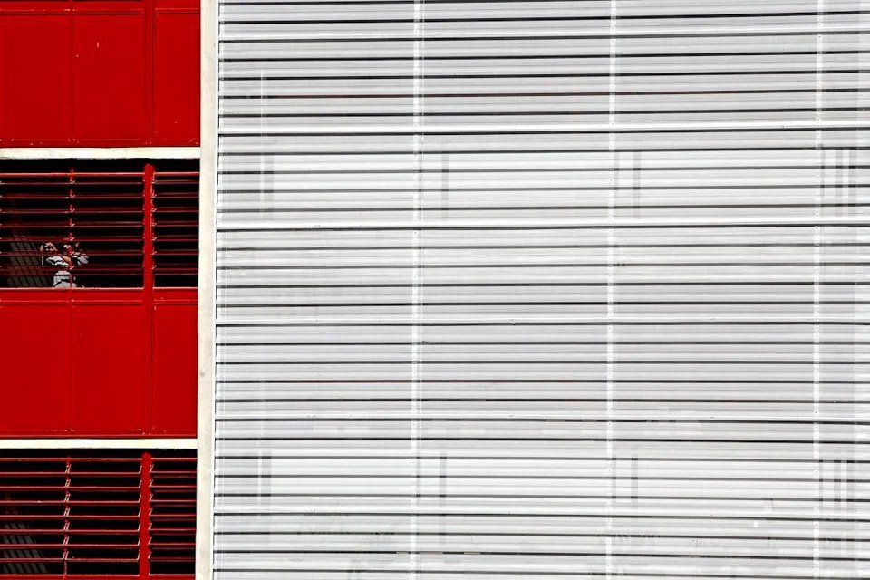 Um close de um prédio vermelho e branco com persianas nas janelas.