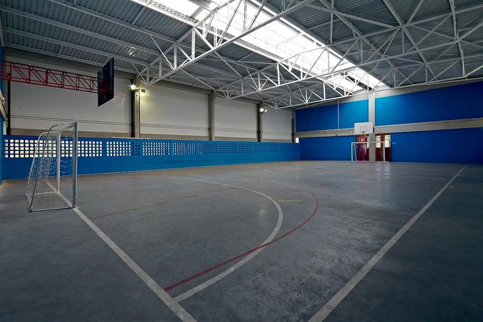 Uma grande quadra de basquete coberta com paredes azuis e brancas