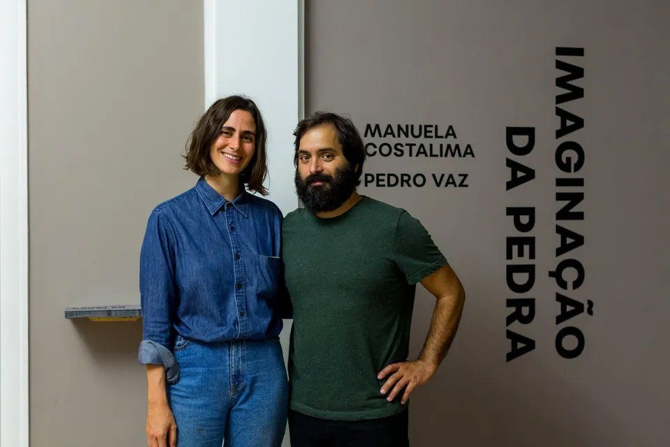 Um homem e uma mulher estão um ao lado do outro em frente a uma parede.