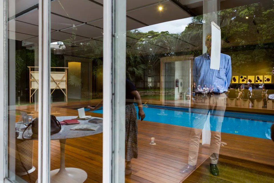 Um homem de camisa azul está parado em frente a uma piscina.