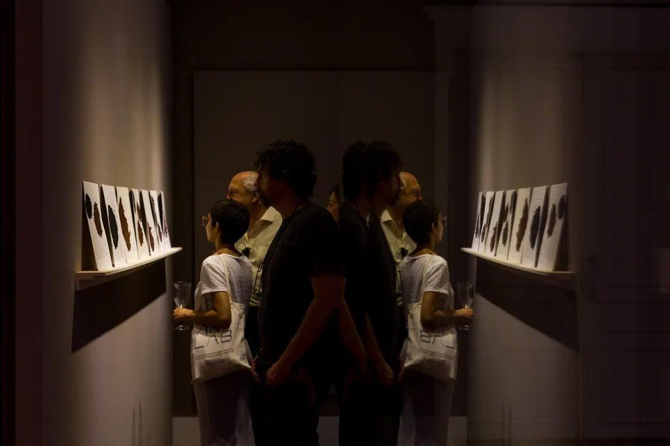 Um grupo de pessoas está em um corredor escuro em frente a um espelho.