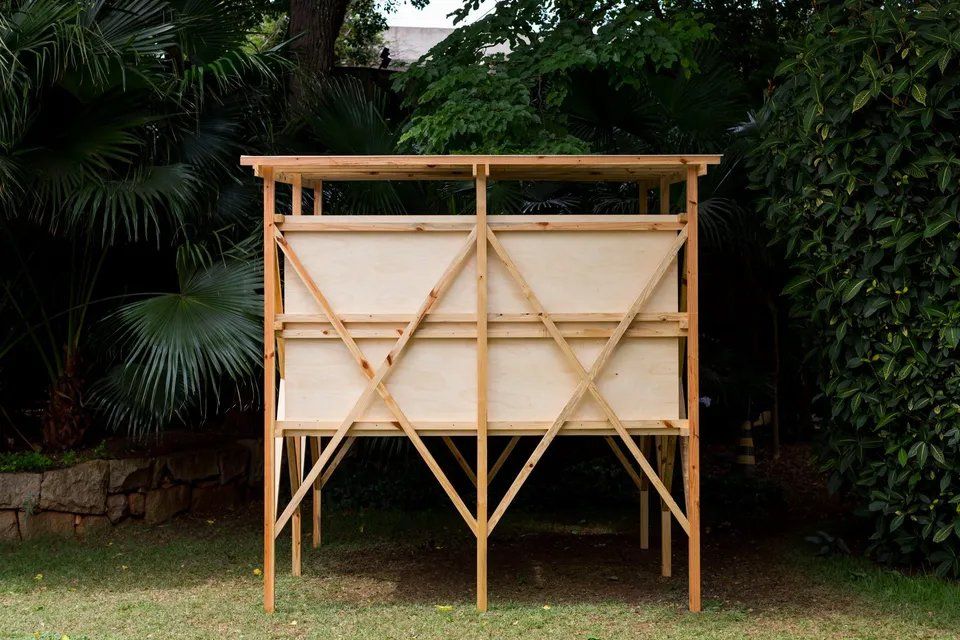 Uma estrutura de madeira está no topo de um campo verdejante.