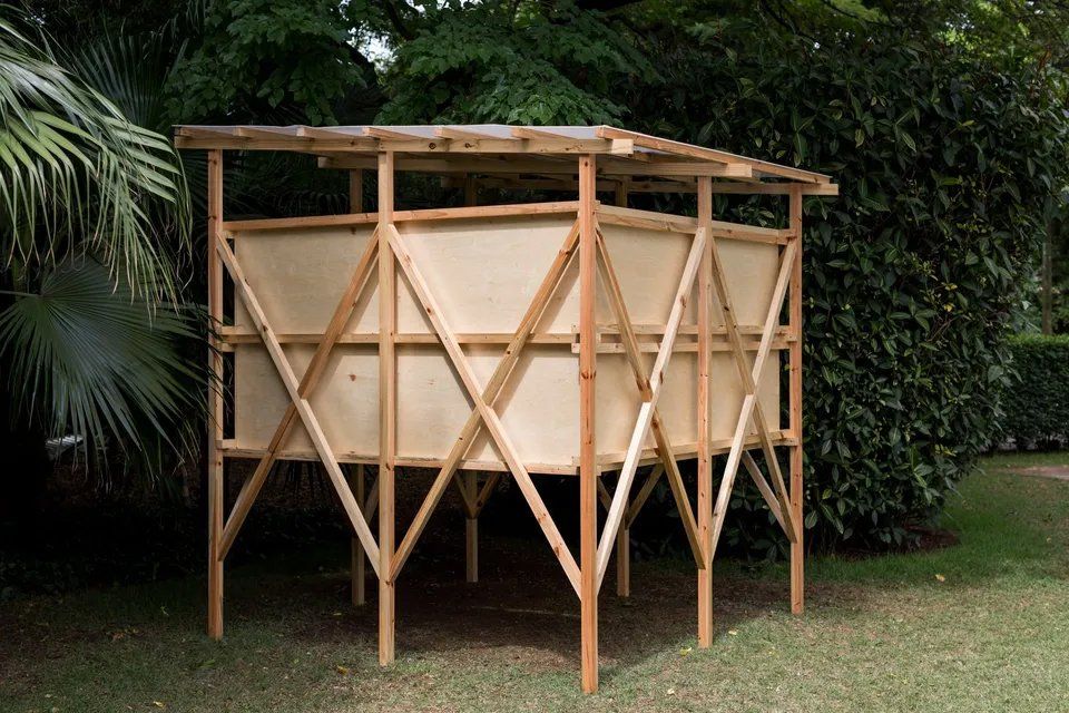 Uma estrutura de madeira está no topo de um campo verdejante.