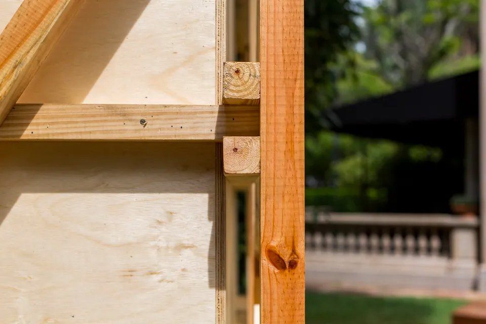 Um close de uma parede de madeira com uma cerca ao fundo.