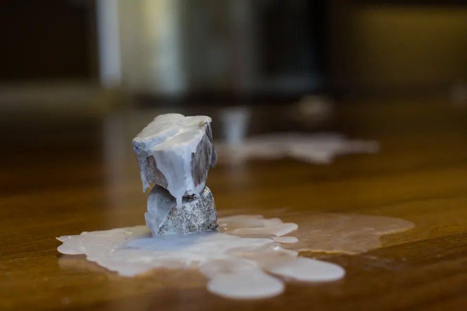 Uma vela está derretendo sobre uma mesa de madeira.