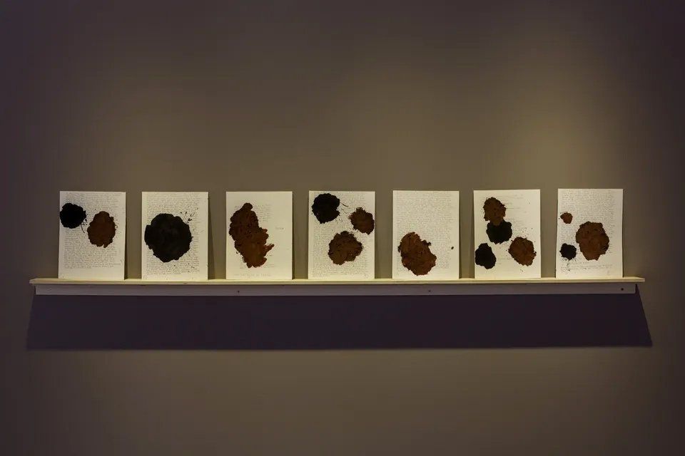 Uma fileira de pinturas em uma prateleira na parede.