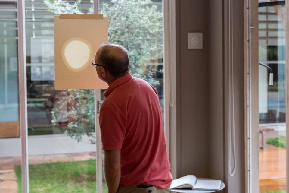 Um homem de camisa vermelha está olhando pela janela.