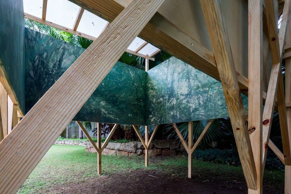 Uma estrutura de madeira com uma lona verde pendurada no teto.