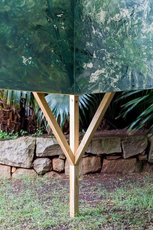 Um poste de madeira está na grama próximo a um muro de pedra.