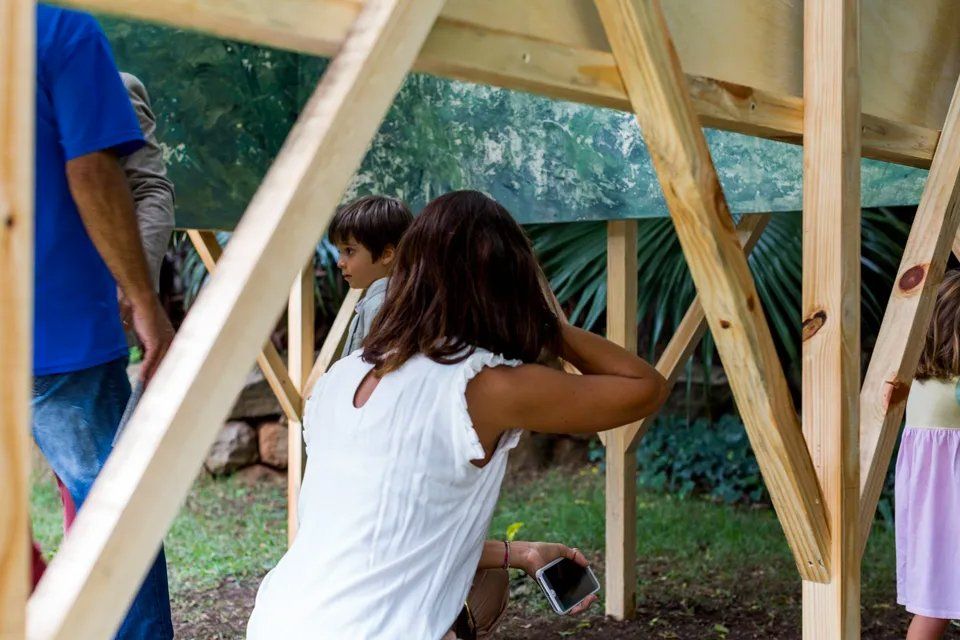Uma mulher de camisa branca está sentada em um balanço de madeira.