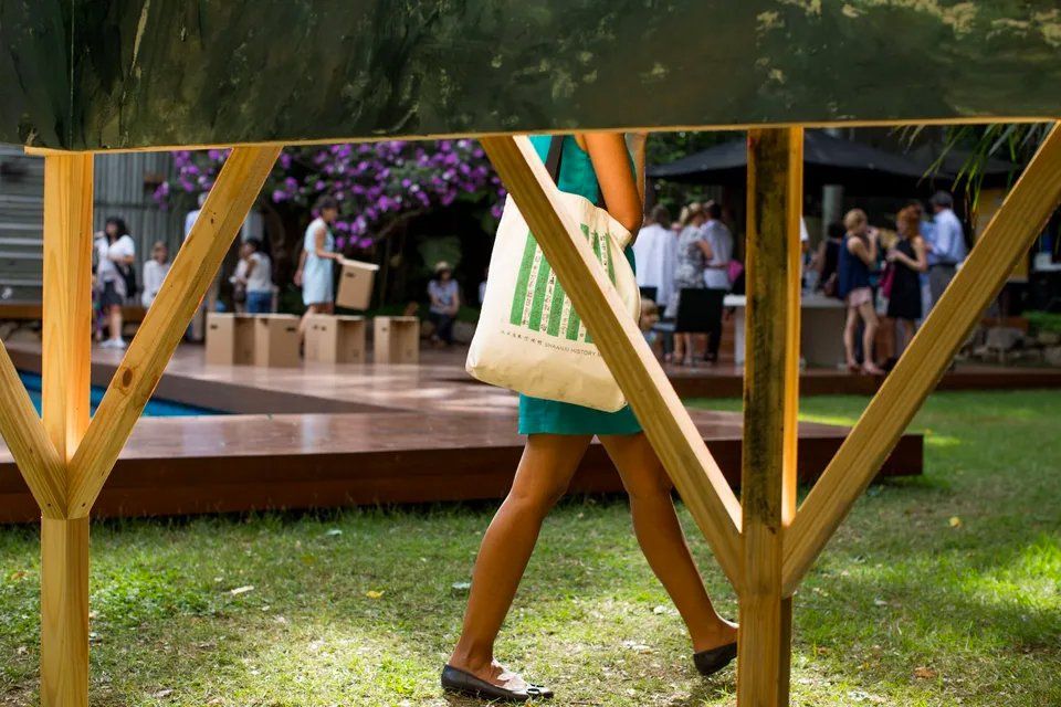 Uma mulher de vestido verde caminha por uma estrutura de madeira em um parque.