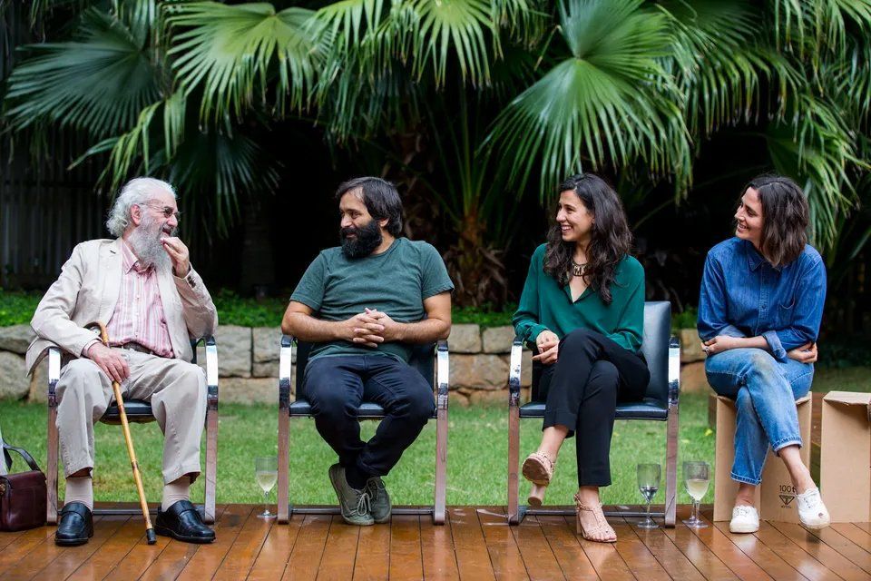 Um grupo de pessoas está sentado em cadeiras em um deck de madeira.