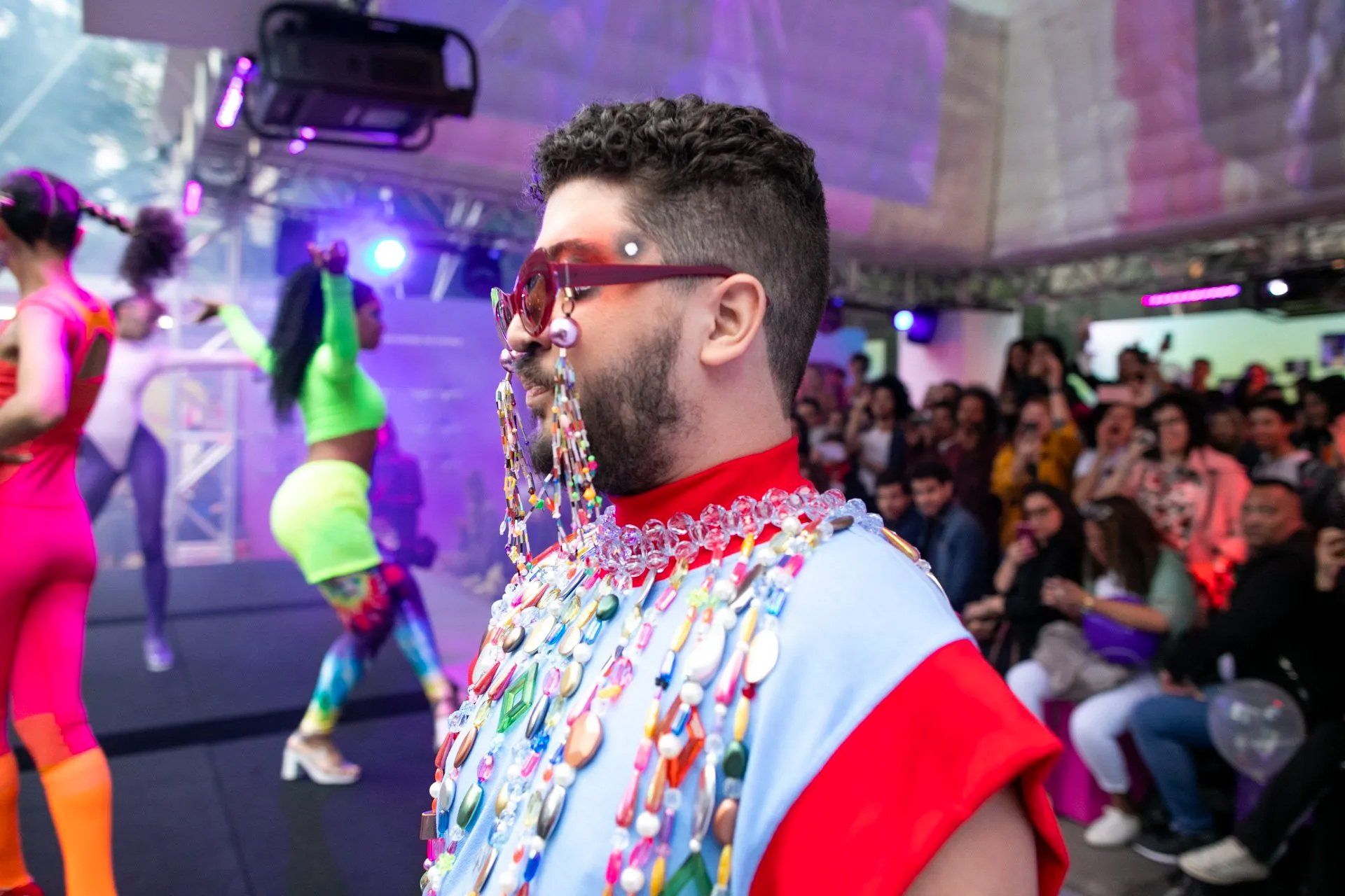 Um homem usando óculos escuros está parado na frente de uma multidão.