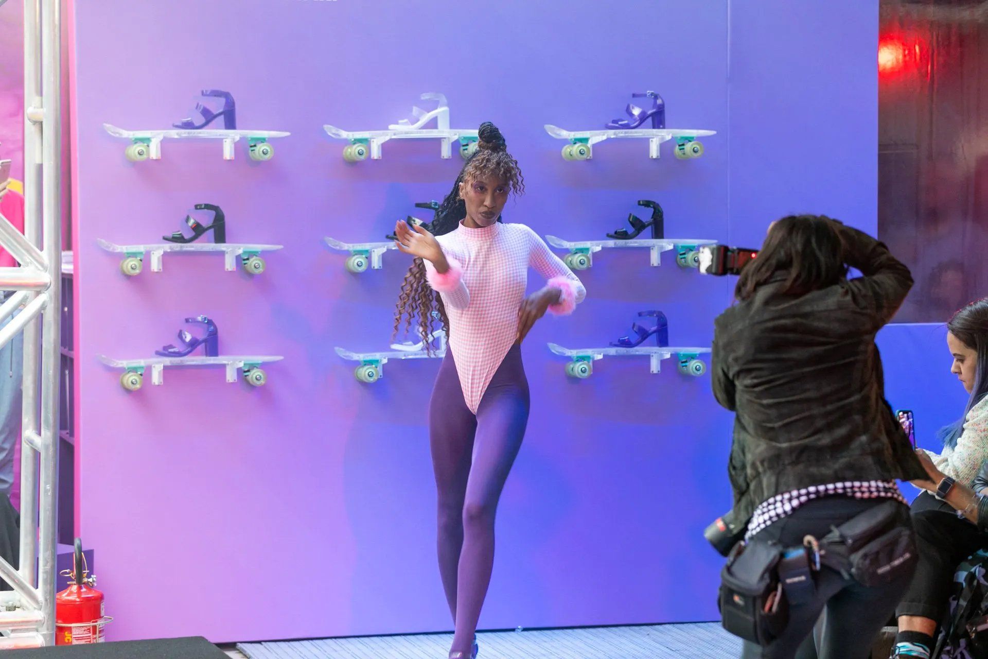 Uma mulher está parada em frente a uma parede com patins.