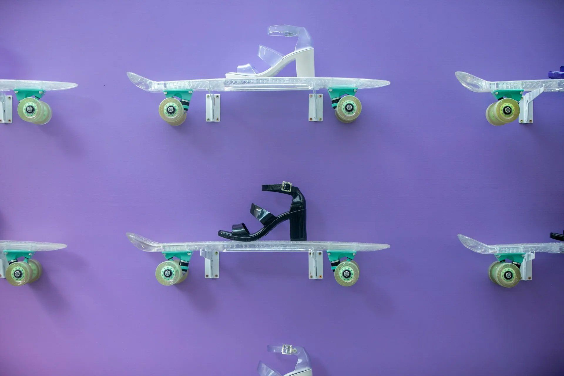 Um par de sapatos está em cima de um skate em uma parede roxa.