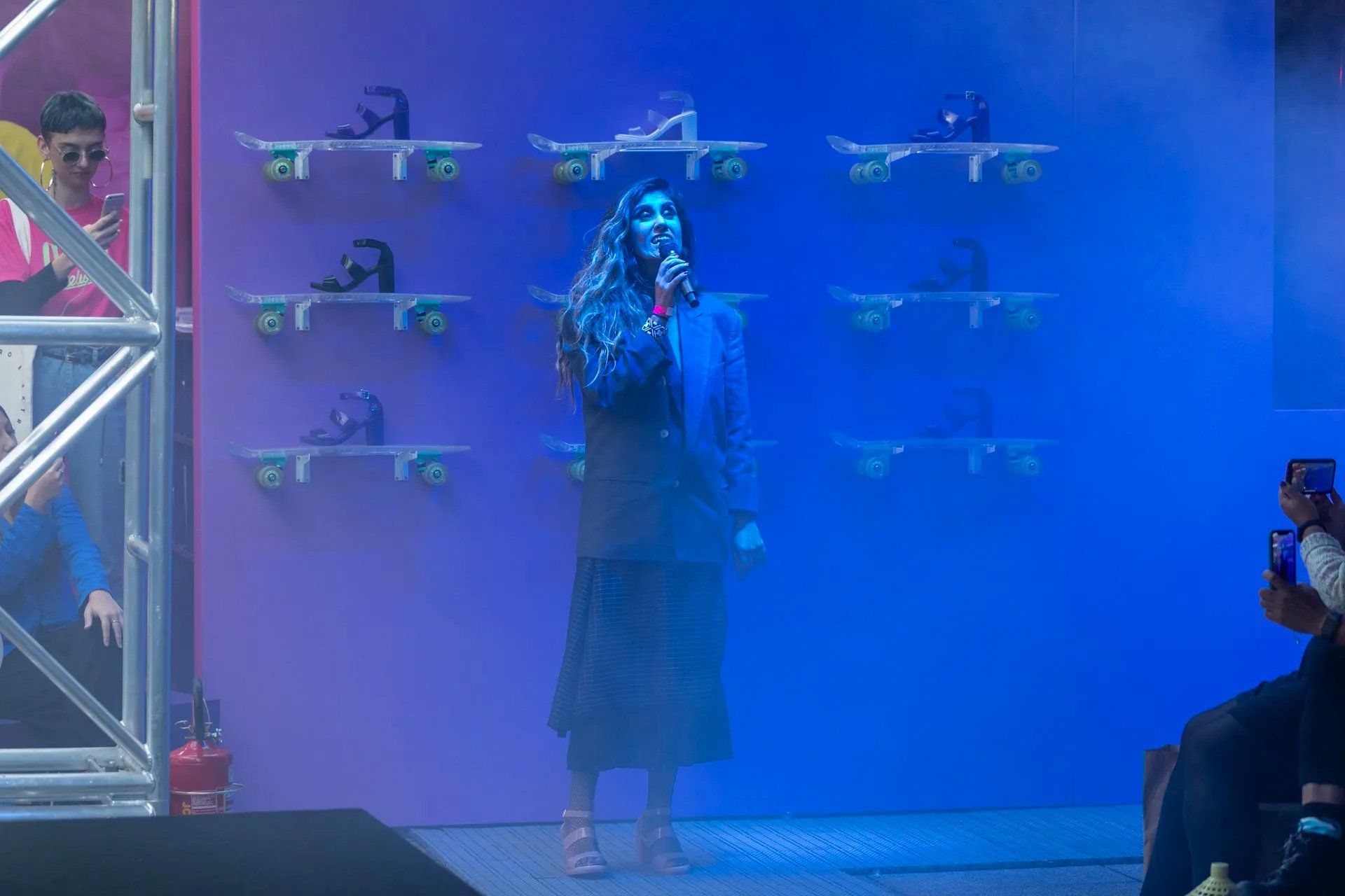 Uma mulher está no palco cantando ao microfone.