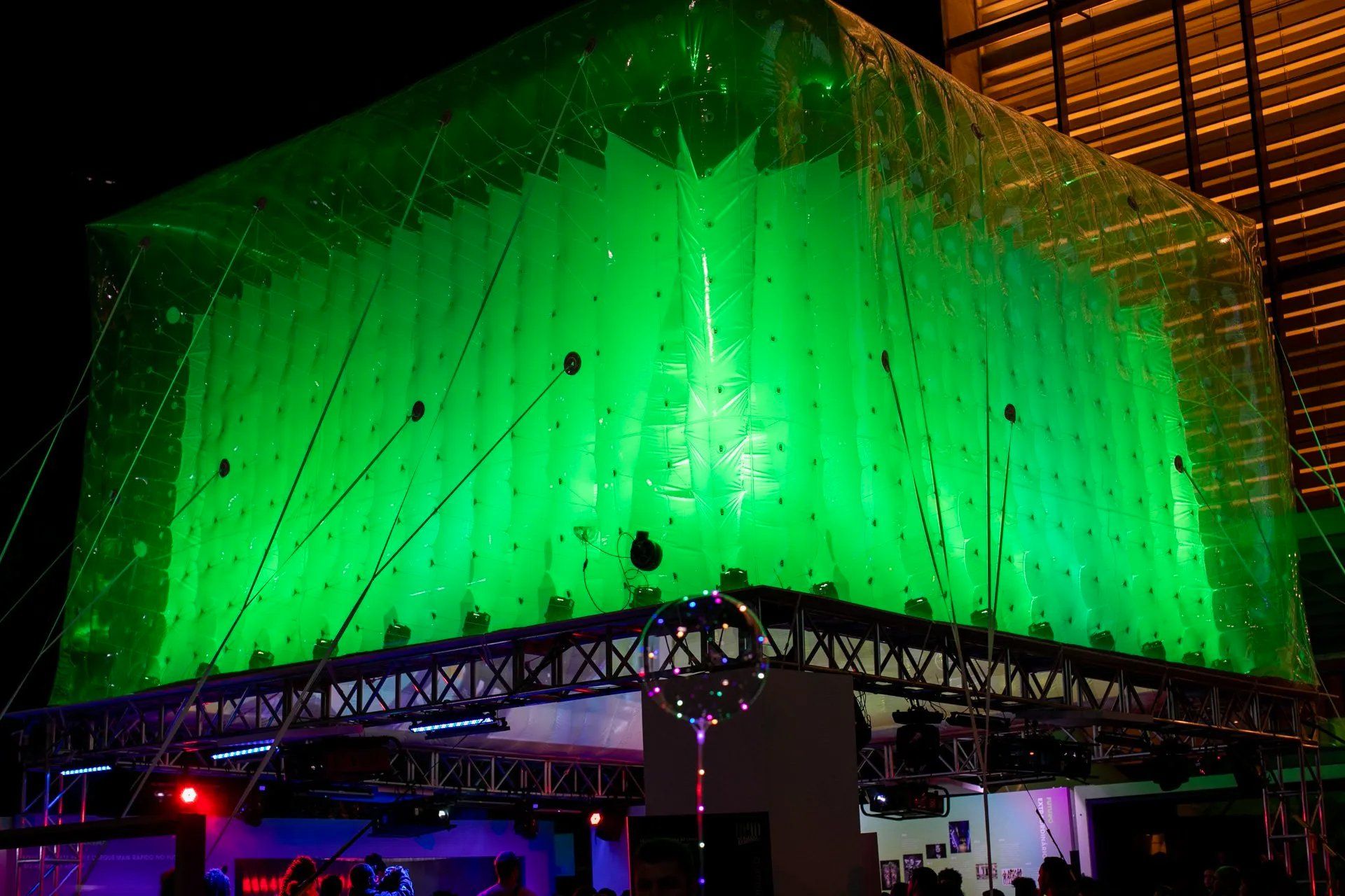 Um grande cubo verde está pendurado no teto de um edifício.