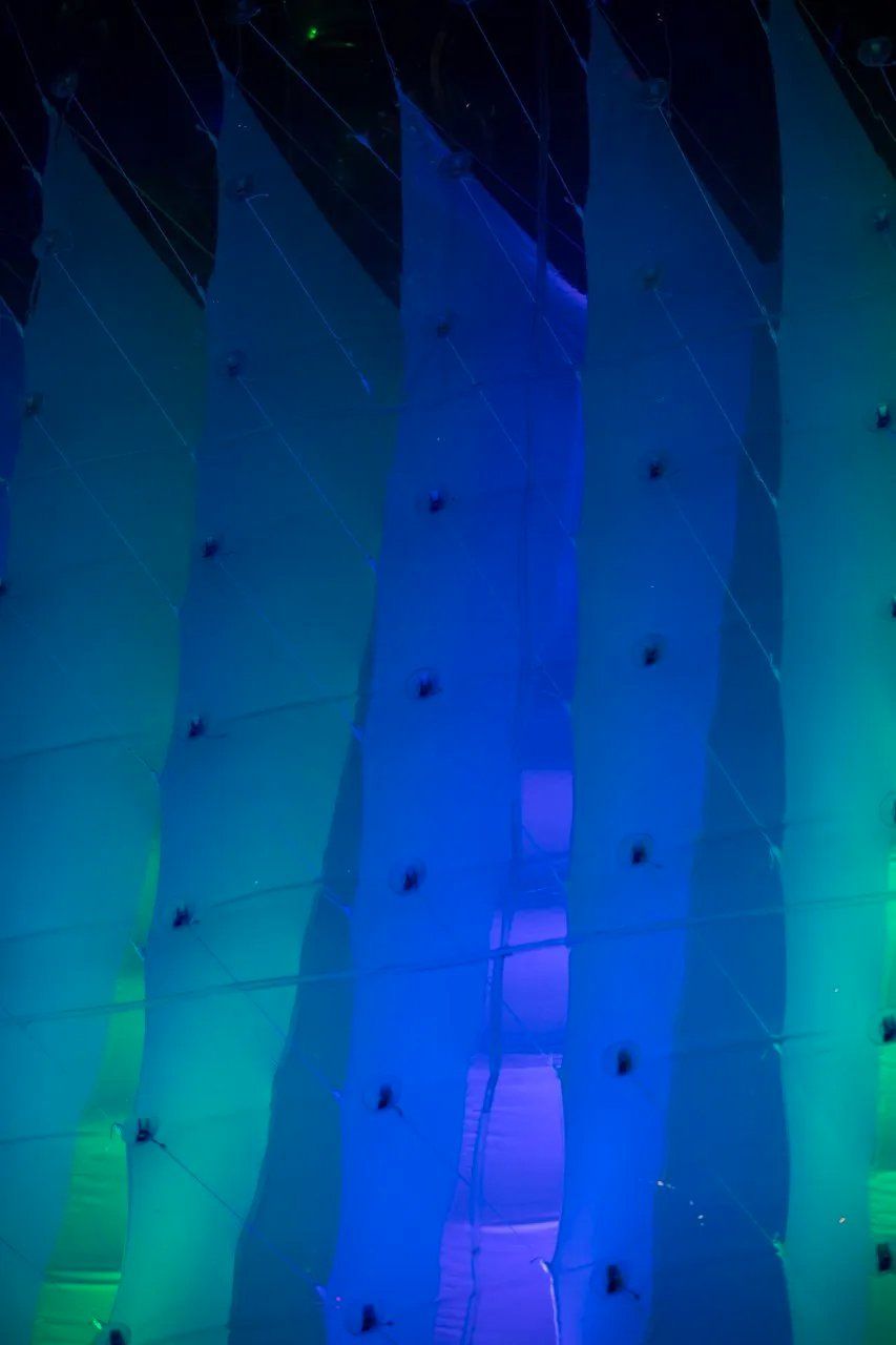 Uma fileira de luzes azuis e verdes penduradas no teto de um prédio.