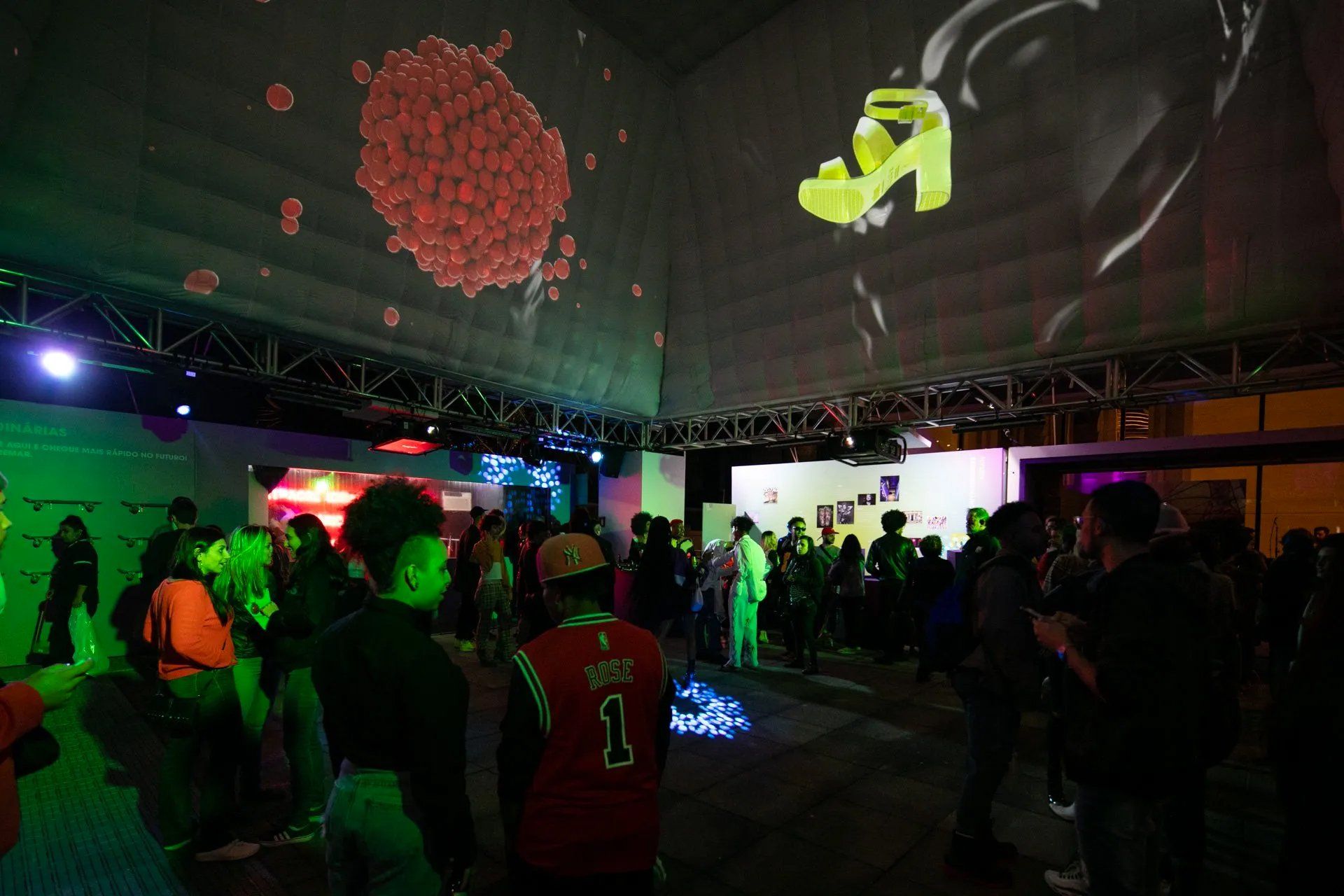 Um grupo de pessoas está em uma sala com uma grande tela projetada na parede.