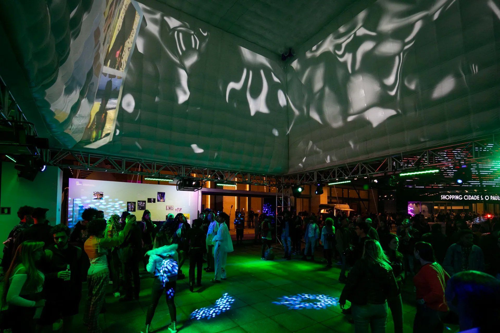 Um grupo de pessoas está em uma sala com luzes verdes no chão.