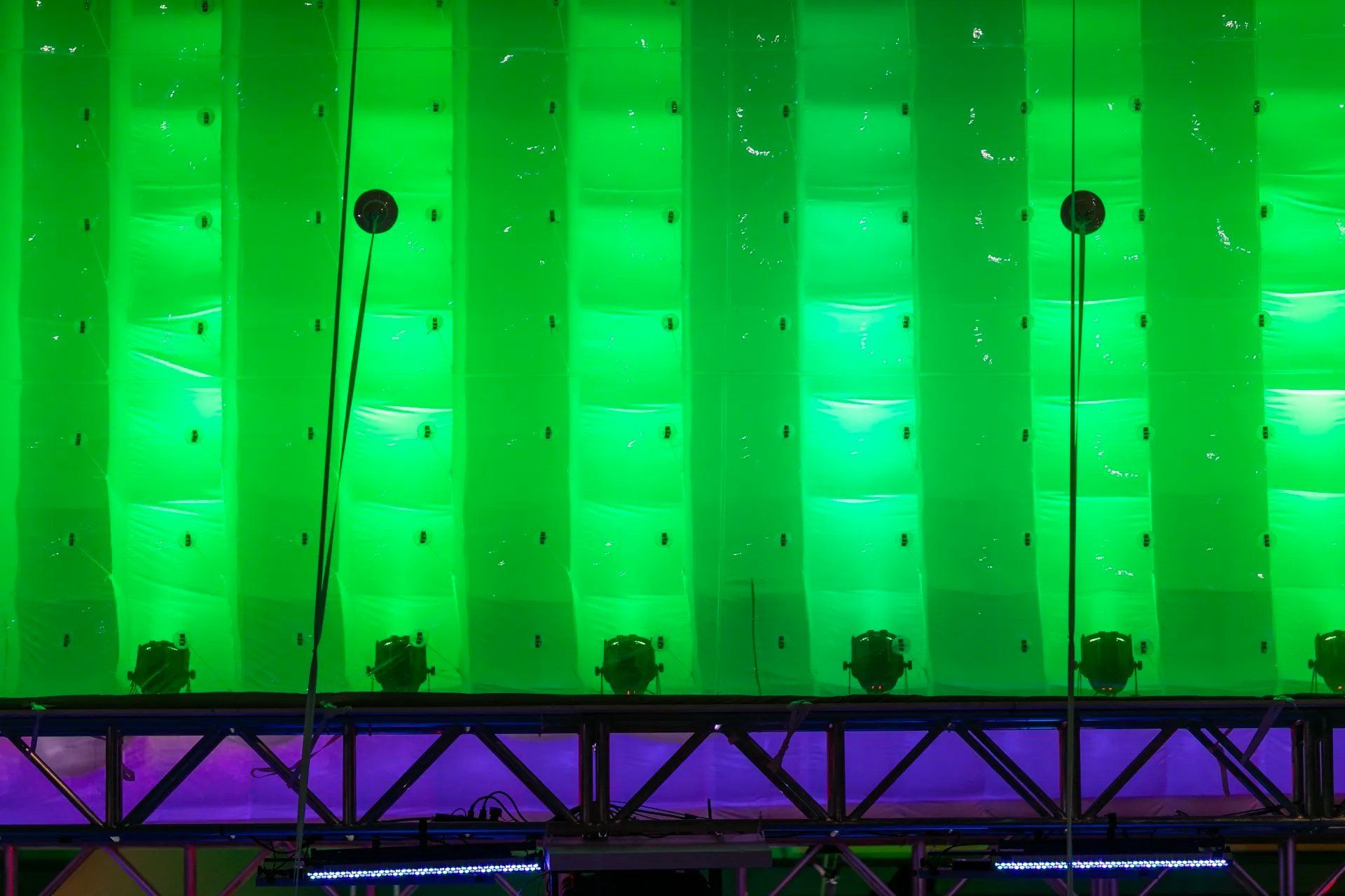 Um monte de luzes verdes estão penduradas no teto de um prédio.