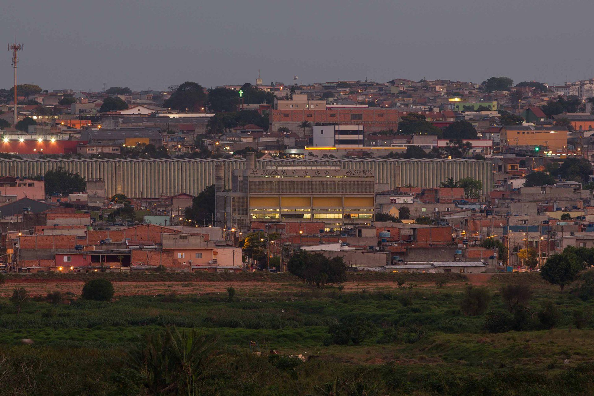 Uma vista aérea de uma cidade à noite com um grande edifício em primeiro plano