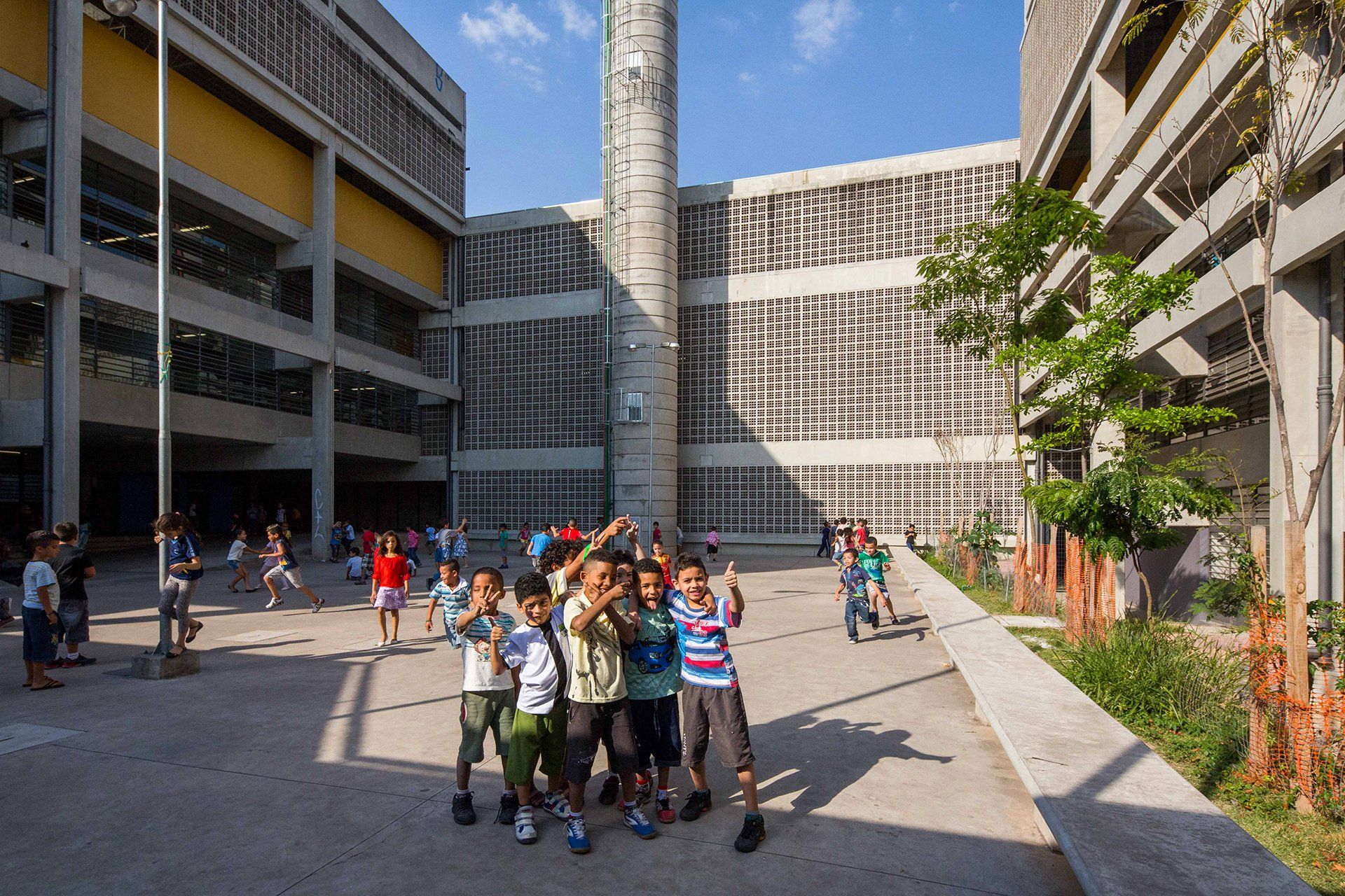 Um grupo de crianças posa para uma foto em frente a um grande prédio.
