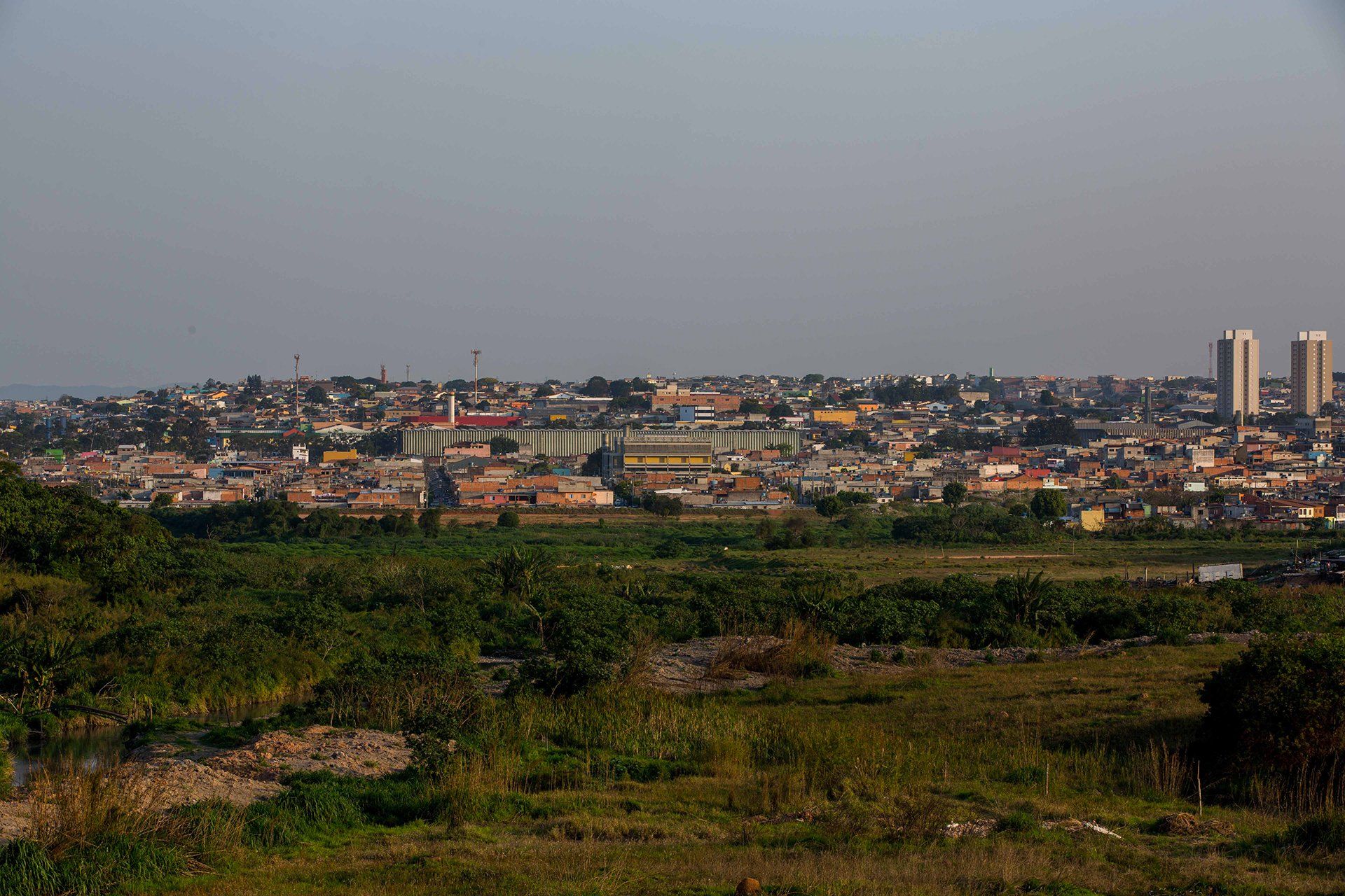 Uma cidade é visível à distância, atrás de um campo gramado.