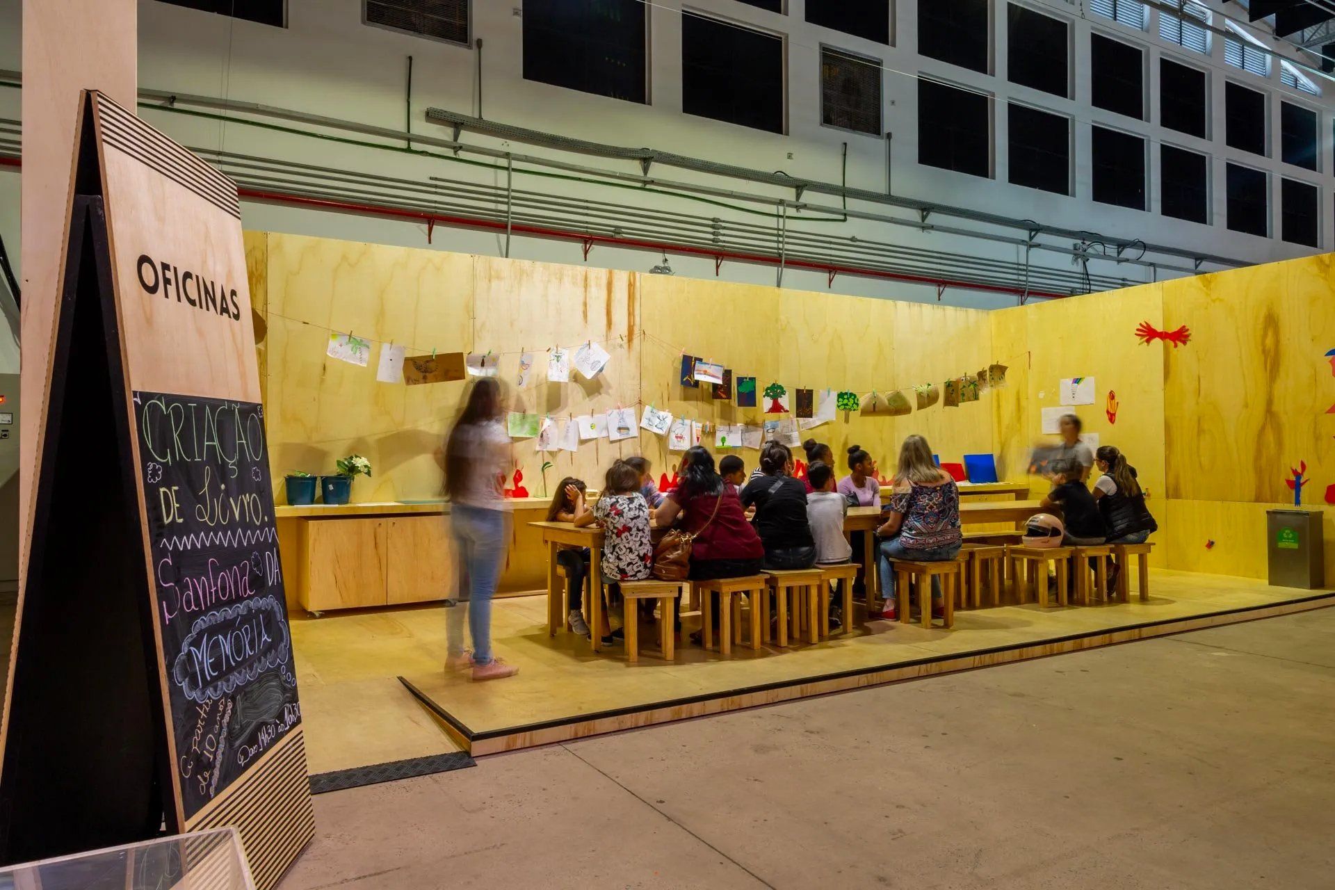 Um grupo de pessoas está sentado em mesas em uma sala.