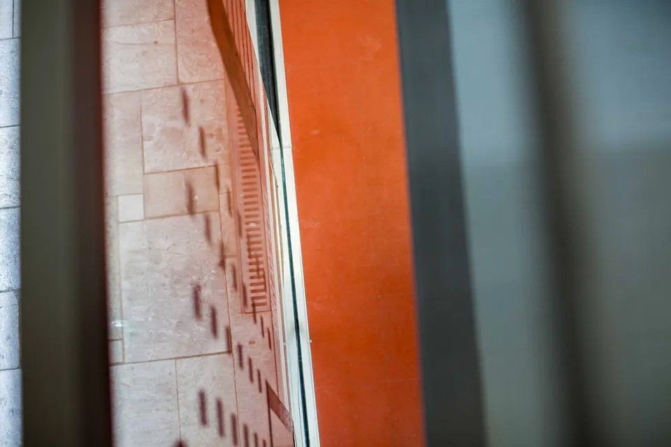 Um relógio está pendurado na parede próximo a uma parede de tijolos.