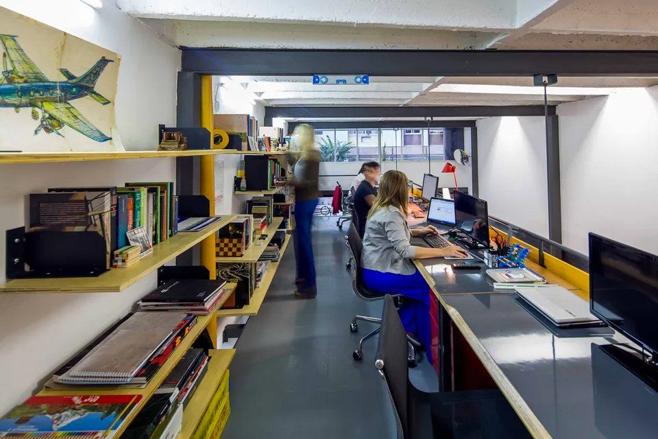 Uma mulher está sentada em uma mesa em um escritório trabalhando em um computador.