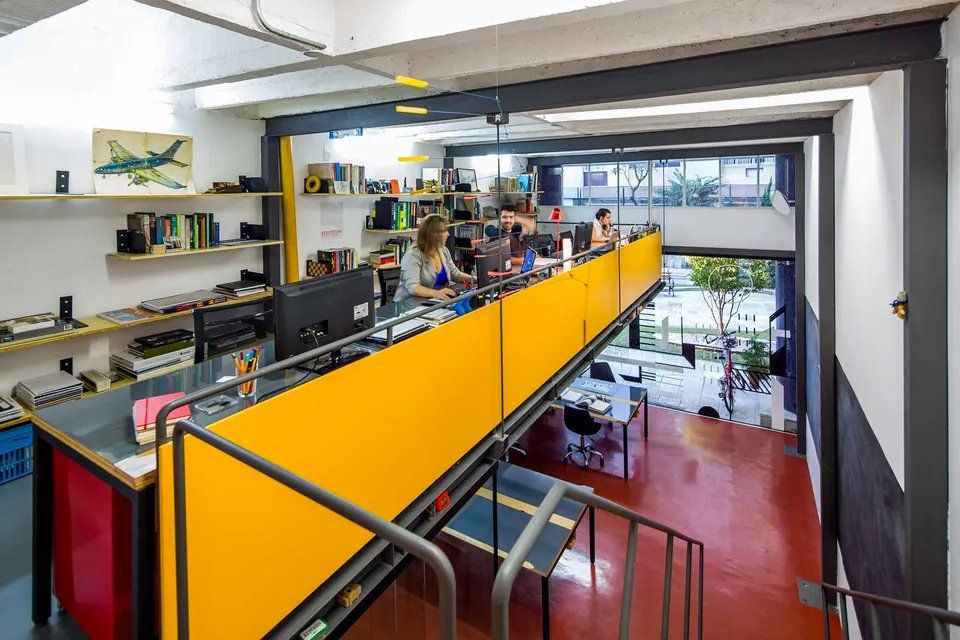 Um grupo de pessoas está sentado em mesas de um escritório.