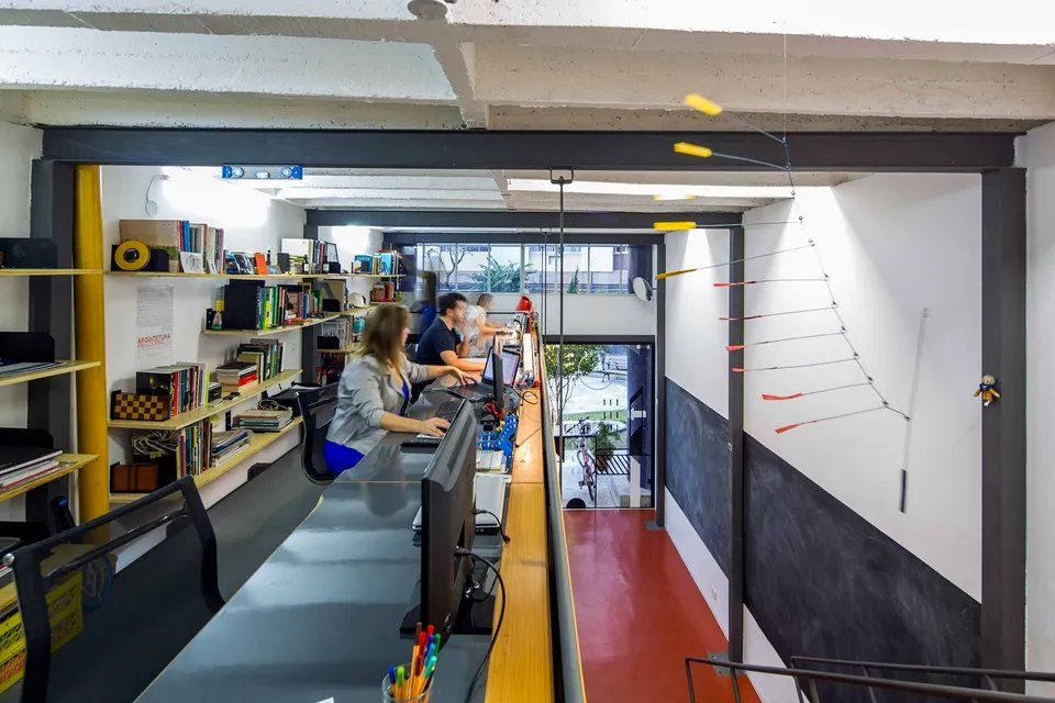 Uma mulher está sentada em uma mesa em um escritório trabalhando em um computador.