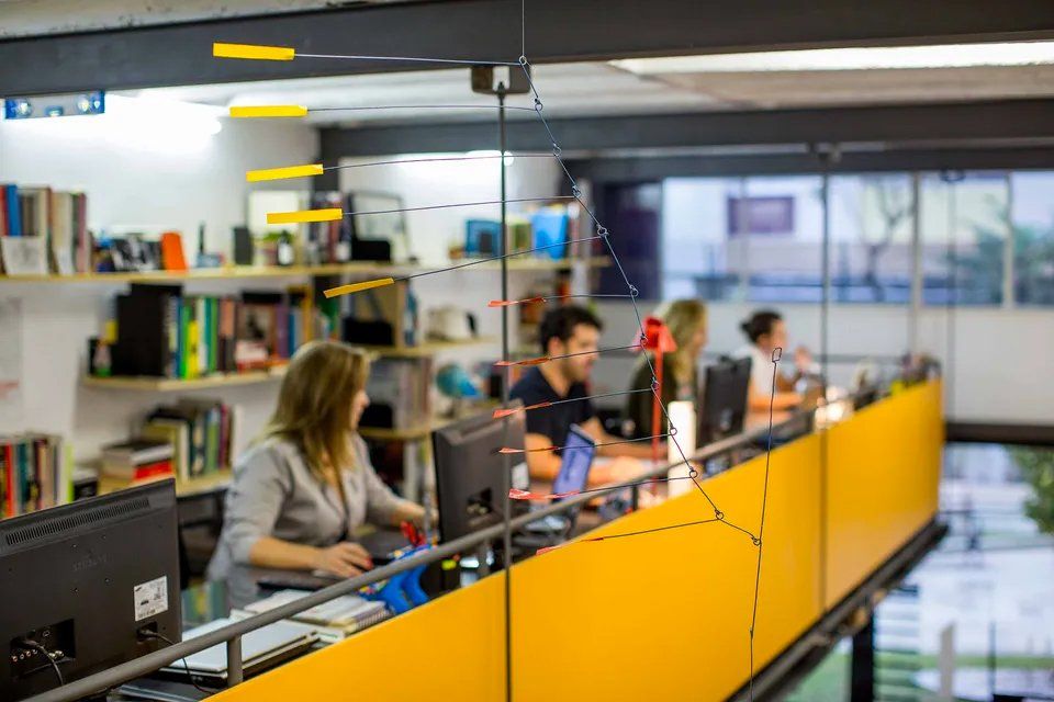 Um grupo de pessoas está sentado em mesas de um escritório.