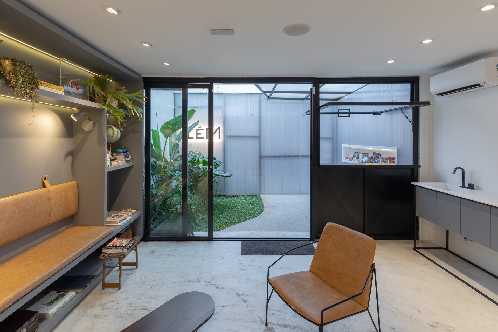 Uma sala de estar com cadeira, banco e portas de vidro deslizantes.