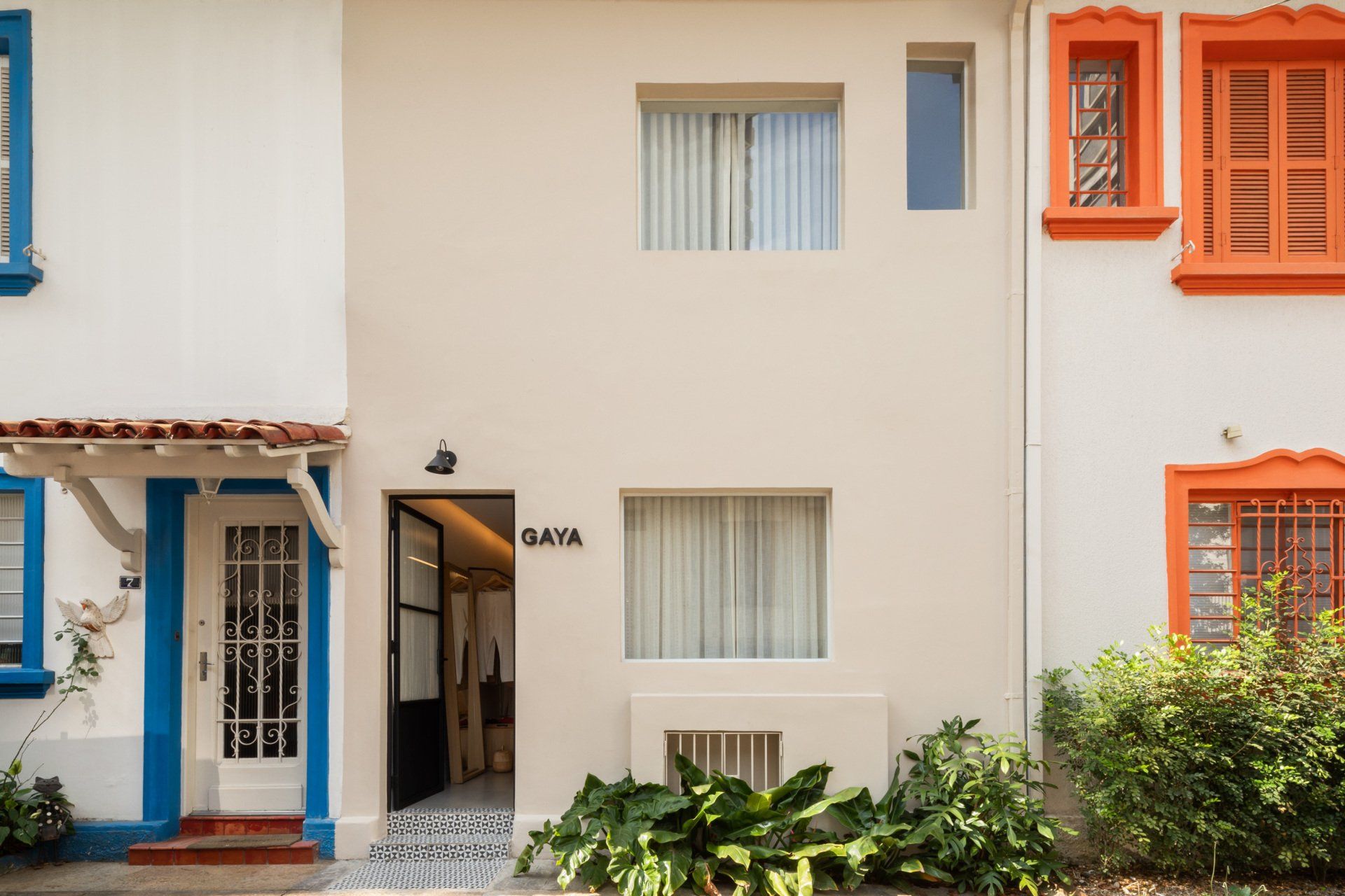 Uma fileira de casas brancas com janelas laranja e azuis