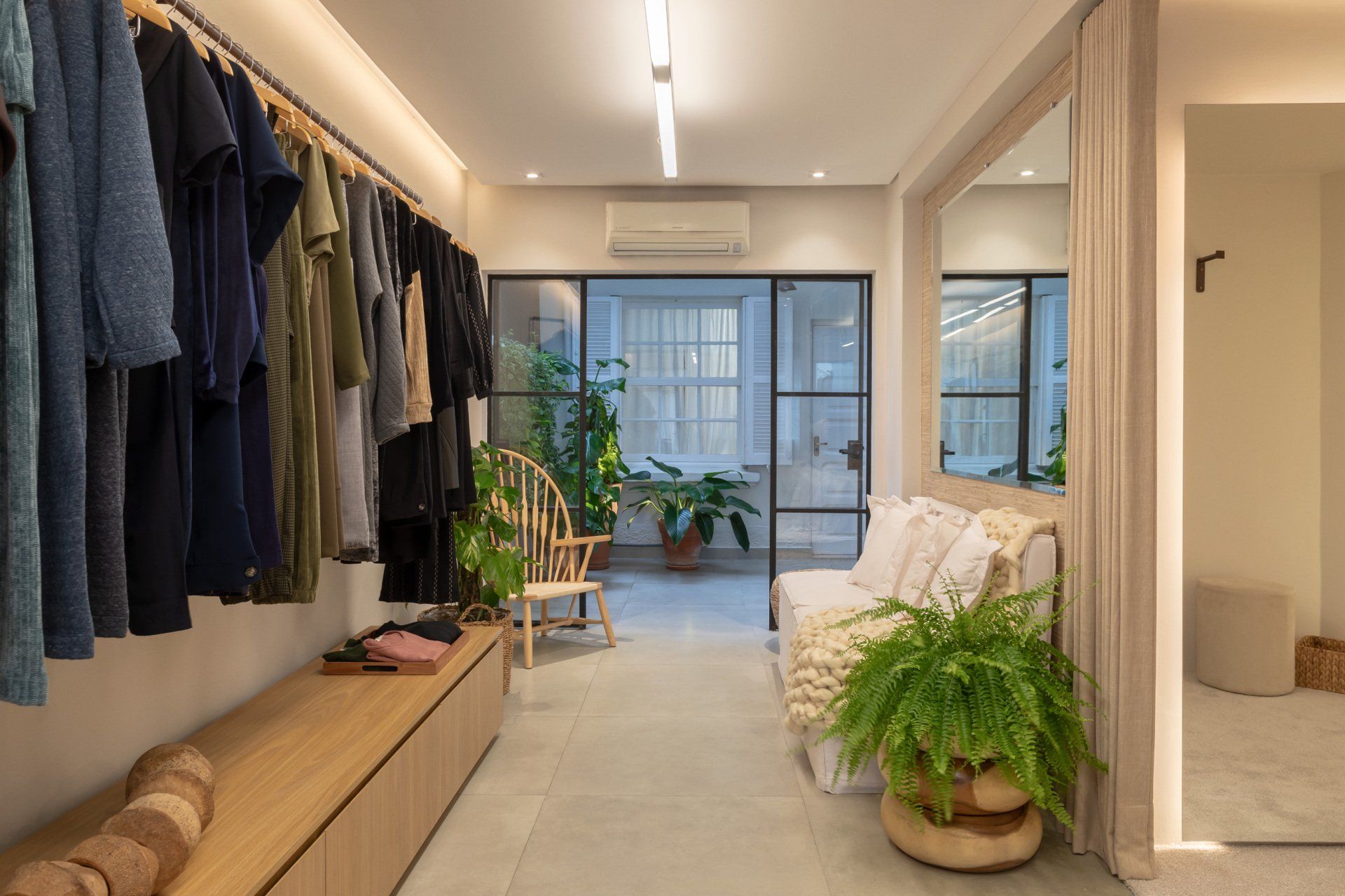 Um camarim com roupas penduradas em cabides e um sofá.