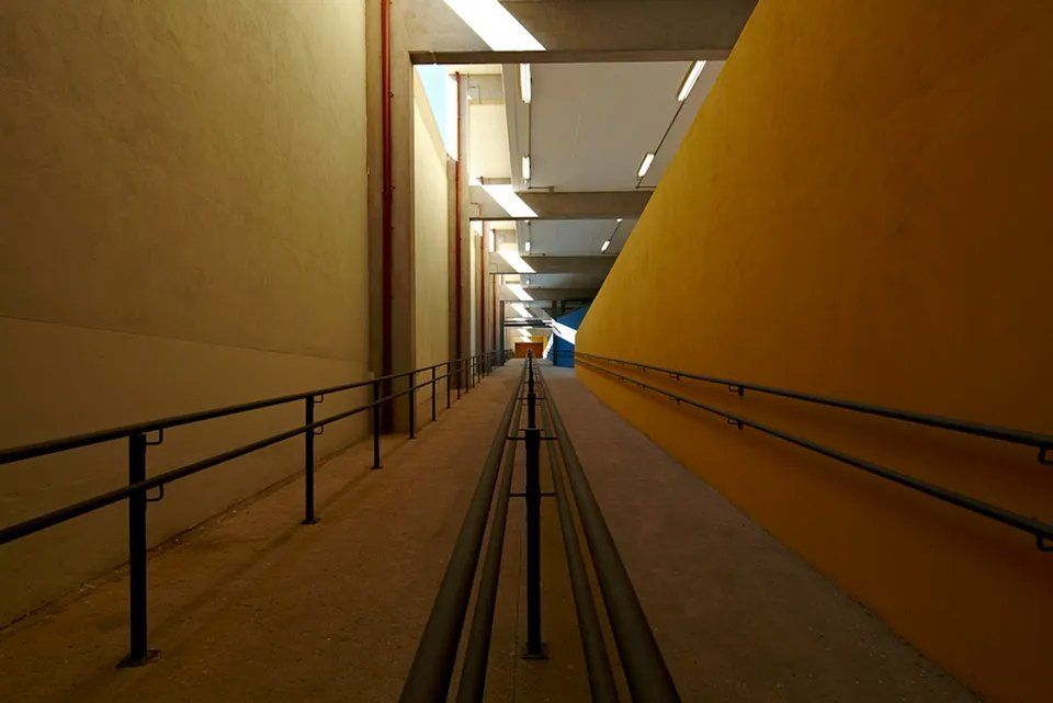 Um longo corredor com uma parede amarela e uma grade preta