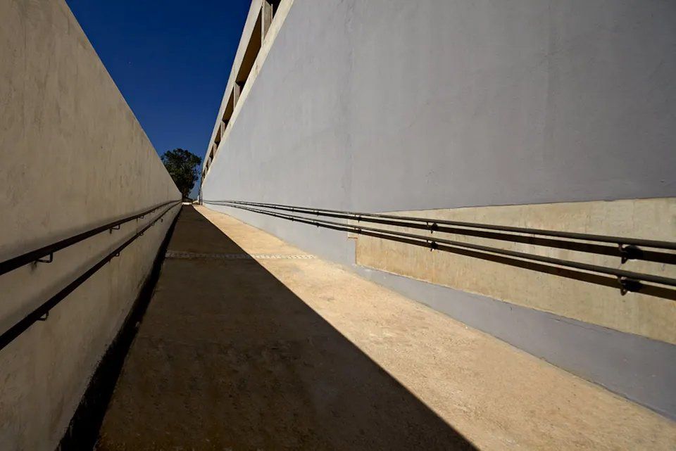 Uma passagem estreita entre dois edifícios com um céu azul ao fundo