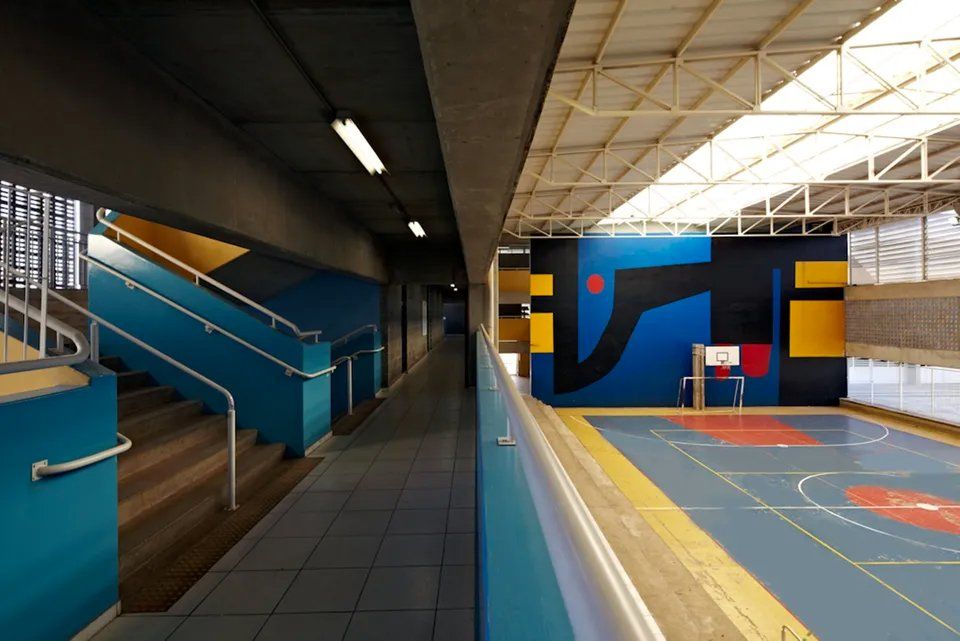 Um corredor com escadas que levam a uma quadra de basquete